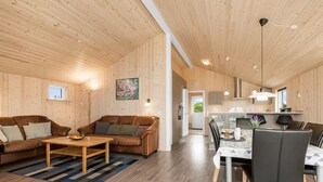 A spacious living area with a wooden floor, a brown leather sofa, a wooden coffee table, and a dining area with a white table and black chairs. - "Clement" - 500m to the fjord by Interhome (Skjern)