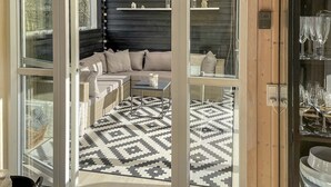 Una habitación acogedora con un sofá modular, una alfombra estampada y un aparador de cristal con copas de vino.