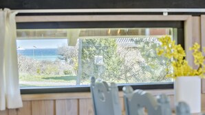 A view from a window with a view of the sea and greenery outside.