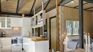 A modern kitchen with white cabinets, a wooden island, and a dining area with a table and chairs.