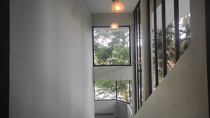 A staircase with a view of greenery outside through large windows. - Mayur Gardens (Sonapur)