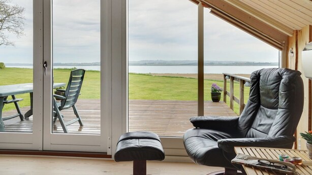 Un espace extérieur moderne, aménagé avec des sièges, offrant une vue sur un lac et des collines lointaines.