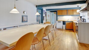 Een moderne keuken met een groot eiland, houten stoelen, hanglampen en uitzicht op de eetruimte.