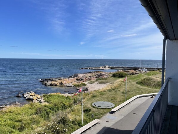 A coastal view with a rocky shoreline, a flag, and a paved walkway.