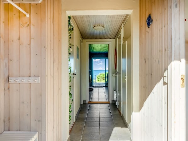 A wooden hallway leading to a door with a view of the ocean.