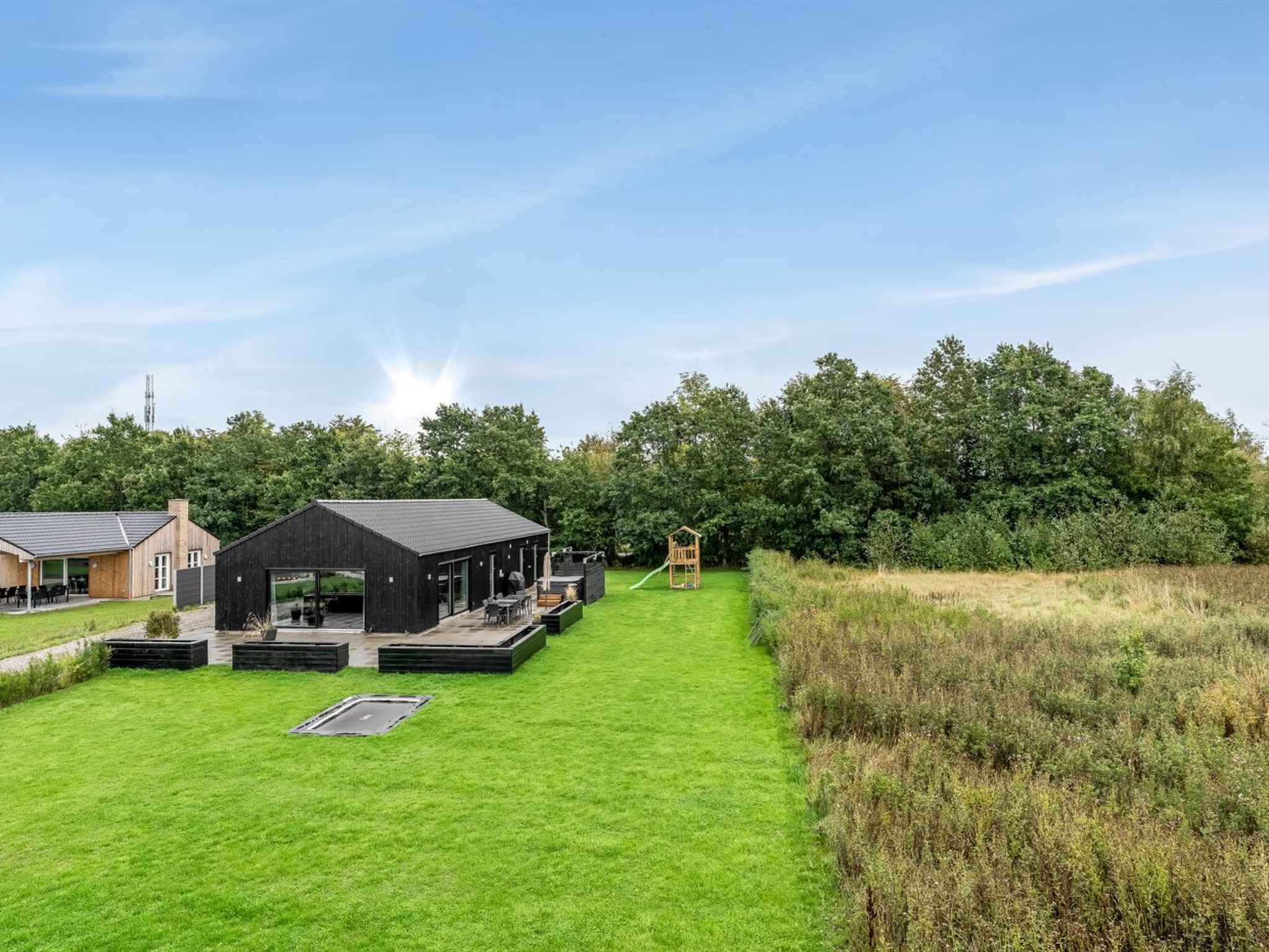 A modern building with a flat roof, a covered outdoor seating area, and a playground.