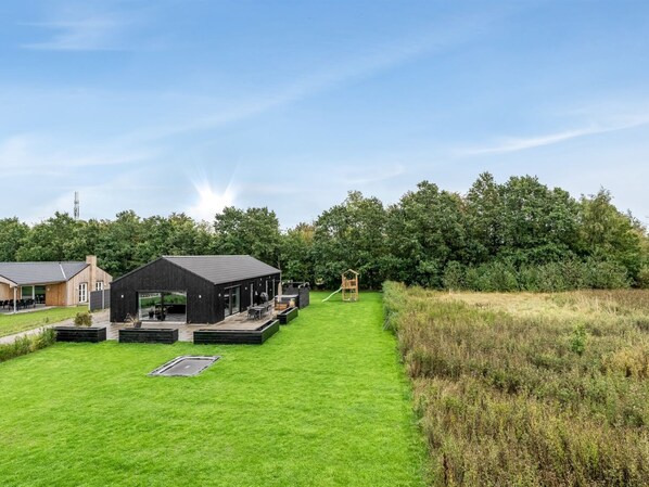 A modern building with a flat roof, a covered outdoor seating area, and a playground.