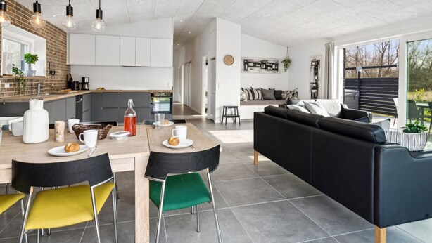 Une cuisine moderne avec un coin repas, un canapé en cuir noir et une grande fenêtre donnant sur un jardin.