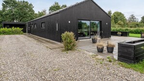 Un bâtiment moderne avec une allée en gravier et des plantes en pot.