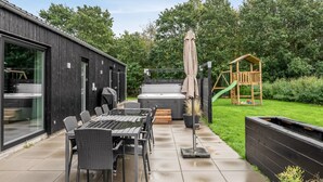 Une terrasse extérieure avec une table et des chaises, un barbecue et une aire de jeux pour enfants.