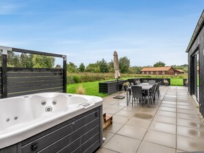 A patio area with a hot tub, outdoor seating, and a view of a wooden house. - "Asel" - 350m from the sea by Interhome (Grenaa)