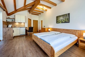 A wooden-framed room with a bed, a desk, and a kitchen area.