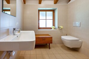 A bathroom with a sink, toilet, and window.