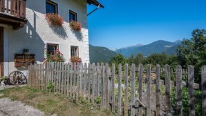 A white building with wooden balconies, a wooden fence, and a mountain backdrop.
