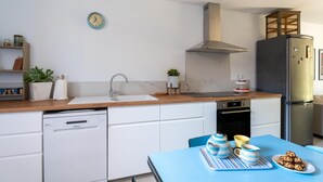 Una cocina moderna equipada con lavavajillas, fregadero, estufa y refrigerador.