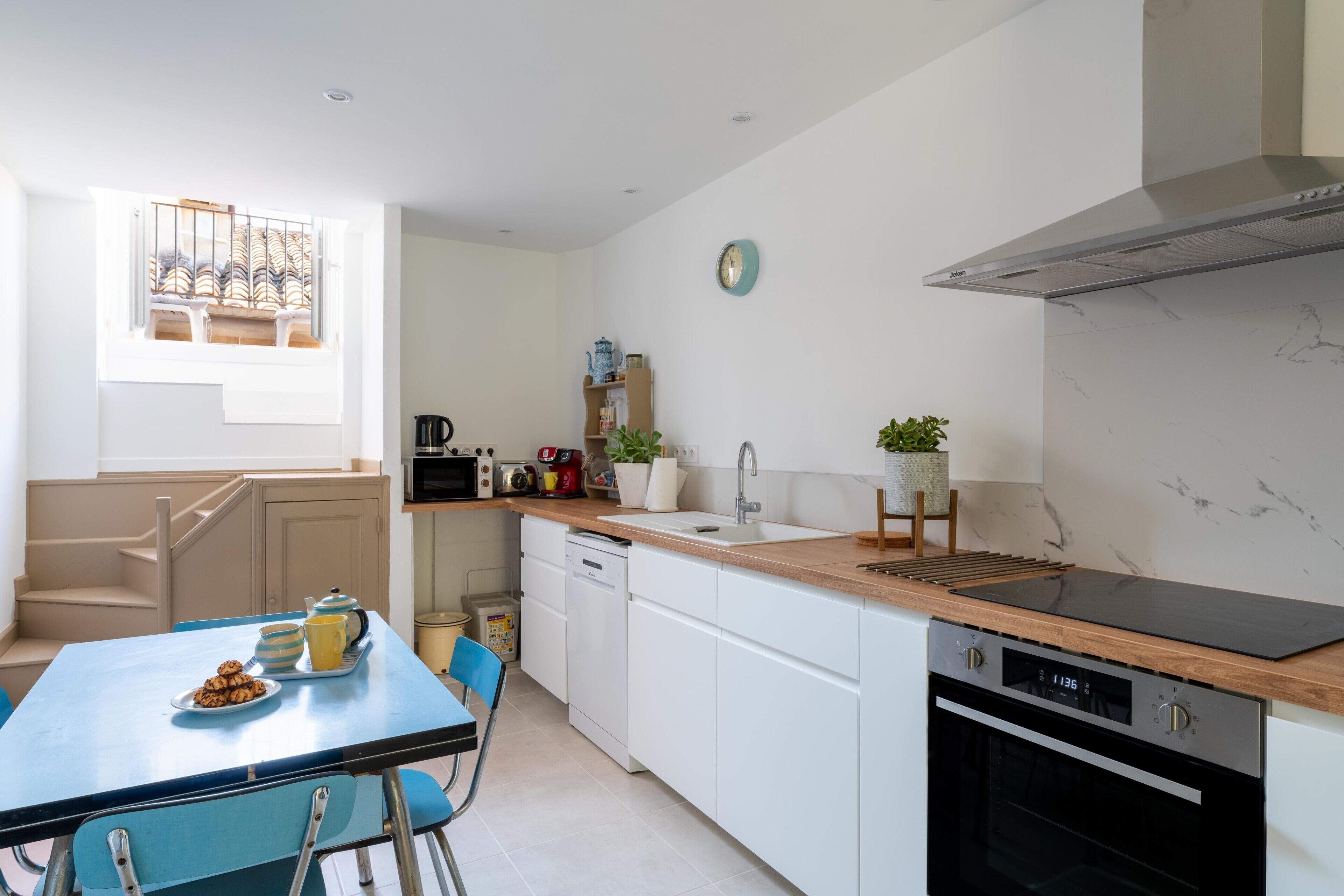 A modern kitchen with white cabinets, a wooden countertop, a built-in oven, and a window with a view.