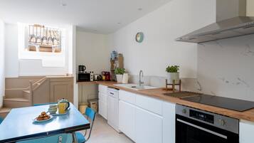 A modern kitchen with white cabinets, a wooden countertop, a built-in oven, and a window with a view.