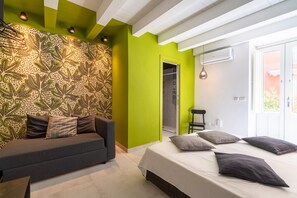 A modern bedroom with a green accent wall, a patterned wall, a bed with pillows, a sofa, and a shower area. - Apartment "Ortigia Dream Rooms 12" with Private Terrace & Wi-Fi (Siracusa)