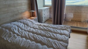 Un dormitorio con cama, mesita de noche, lámpara, cómoda y ventana con cortinas.