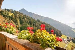 Un balcon en bois offrant une vue sur un paysage montagneux et un village situé en contrebas.