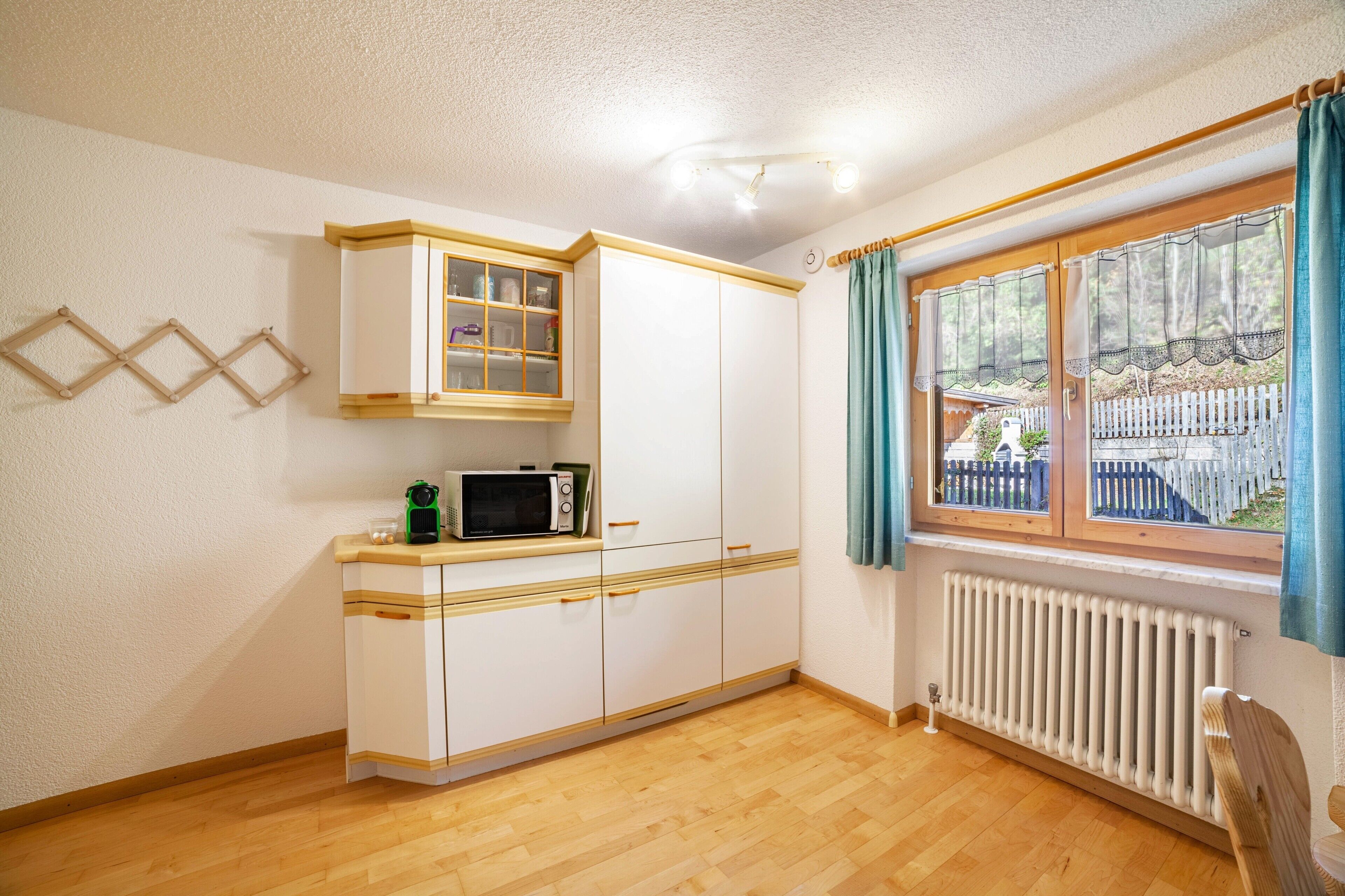 A kitchen with white cabinets, a microwave, and a window with curtains.