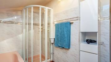 A bathroom with a glass shower enclosure, a white cabinet, and a blue towel.