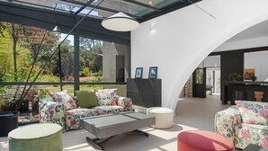Ein modernes Interieur mit Glasdecke, einer Sofagarnitur, einem Couchtisch und einem roten Hocker.