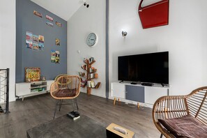 Un salon moderne avec un téléviseur, une bibliothèque et une horloge murale.
