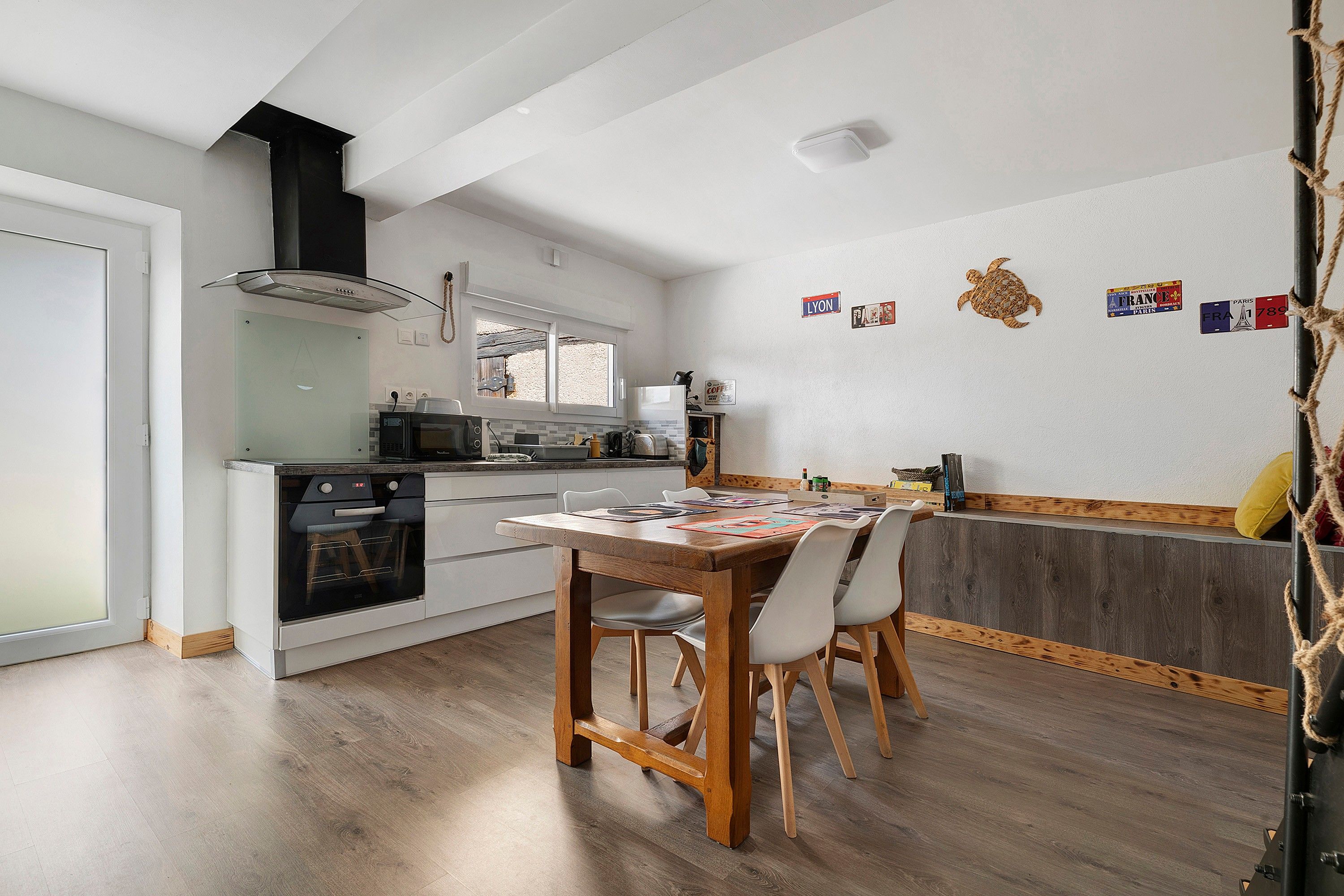 Une cuisine moderne avec un coin repas, un plancher en bois et une vue sur l’extérieur.