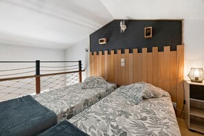 Et soveværelse med køjeseng, træsenggavl, et sengebord med lampe og en rebsikkerhed.