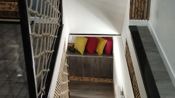 Un llit amb estructura de fusta, una barrera de protecció i un matalàs amb almoadines.