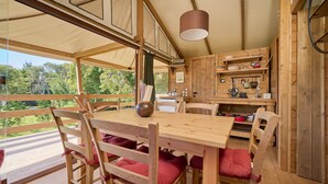 Un tavolo da pranzo in legno con sedie, un lampadario e vista sull'esterno.