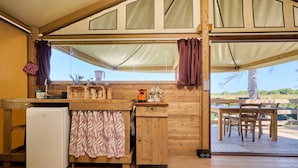 Un intérieur en bois comprenant un coin cuisine, une table à manger et une vue sur l’extérieur.
