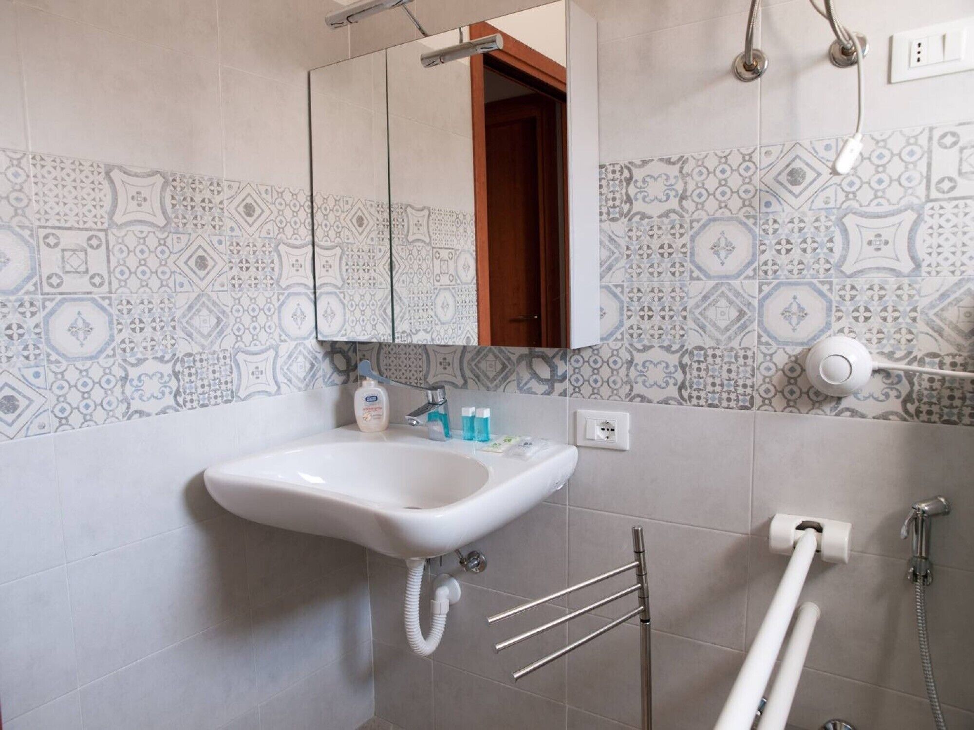Ein Badezimmer mit Waschbecken, Spiegel, Handtuchhalter und Dusche.