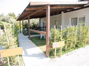 A covered outdoor seating area with wooden beams and a concrete path leading to a building. - Farmhouse 'Bilocale Vicino Al Mare' with Private Garden, Wi-Fi and Air Conditioning (Piombino)