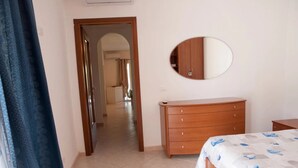 Une chambre à coucher comprenant un lit, une commode, un miroir et une porte donnant sur une autre pièce.
