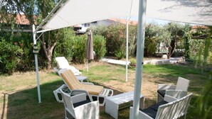 Une terrasse aménagée avec du mobilier d’extérieur, notamment un fauteuil de relaxation et un canapé, placée sous une tonnelle blanche.