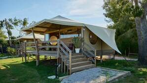Eine Zelthattee mit einer Holzterrasse, Sitzgelegenheiten im Freien und einem Blumentopf.