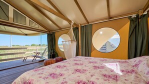 Eine Zelteinrichtung mit Bett, einer Hängematte und Blick ins Freie.