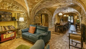 An interior with a stone archway, a sofa, a dining table, and a bookshelf. - Farmhouse 'Mas Alba' with Mountain View, Private Pool and Wi-Fi (Terradelles Girona)