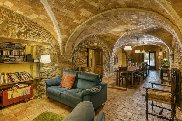 Un interior con un arco de piedra, un sofá, una mesa de comedor y una estantería.