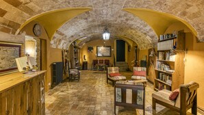 An arched room with a wooden reception desk, seating area, and bookshelves. - Farmhouse 'Mas Alba' with Mountain View, Private Pool and Wi-Fi (Terradelles Girona)