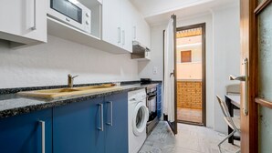 A compact kitchen with a microwave, washing machine, and a sink. - Apartment 'Salou Centro' with Private Terrace (Salou)