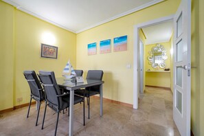 Un'area pranzo con un tavolo e sedie, un quadro incorniciato appeso al muro e uno specchio con una cornice decorativa.
