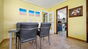 A dining area with a table and chairs, a kitchen in the background, and a door leading to another room. - Apartment 'Salou Centro' with Private Terrace (Salou)