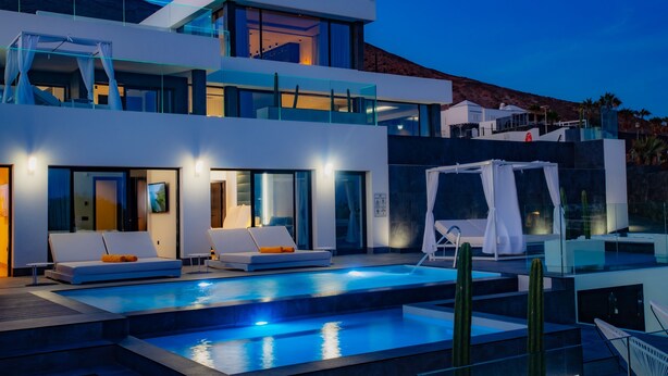 Ein modernes Hotel mit Pool, Liegestühlen und Bergblick.