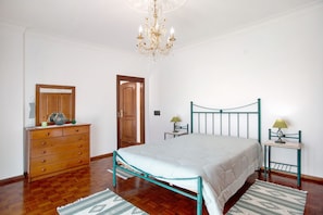 Quarto com cama, penteadeira e duas mesas de cabeceira.