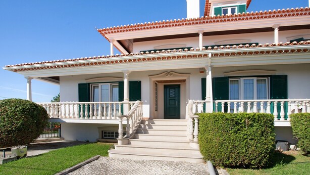 Une maison à deux étages dotée d’un balcon, d’une porte d’entrée et d’un escalier menant à l’entrée.