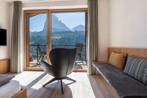 A modern room with a balcony, a sofa, a chair, and a TV.