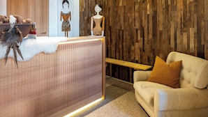 A reception area with a wooden wall, a reception desk, a sofa, and a poster on the wall. - Vista Dolomites Apartment "Harmony" with Mountain View, Private Garden & Wi-Fi (S. Cristina)